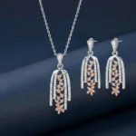 Elegant two-tone drop pendant and earrings set featuring 925 silver and rose gold floral accents on a luxury jewelry display.