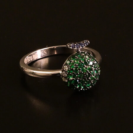 "Silver ring adorned with sparkling green crystals displayed on a dark surface."