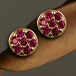 "Pair of sterling silver stud earrings with vibrant pink crystal accents arranged in a circular pattern, displayed on a wooden surface."