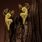 "Pair of minimalist silver rose gold stud earrings shaped like delicate deer, displayed on a wooden surface."