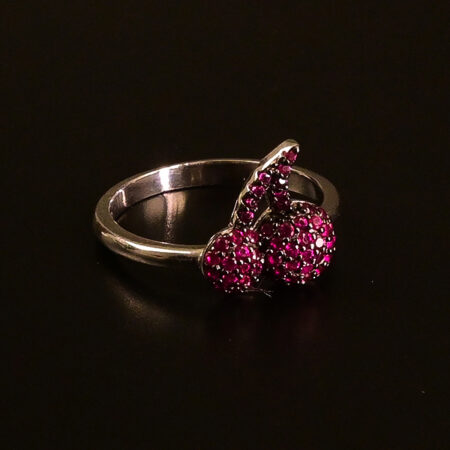 "Silver statement ring with bright cherry-inspired sparkling stones displayed on a dark surface."