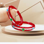 Pair of silver bangles with red enamel, adorned with blue and green circular stones