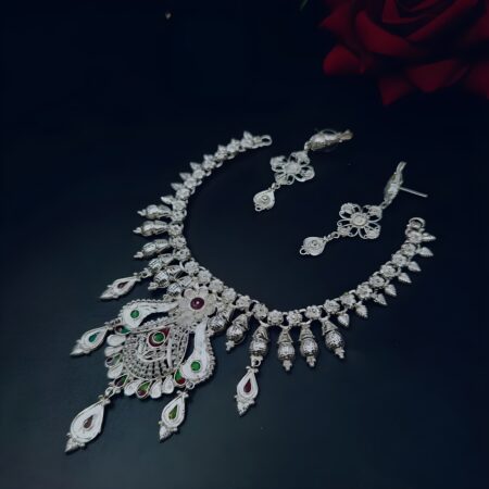 Handcrafted silver-plated necklace set with matching earrings, adorned with red and green enamel teardrop accents, displayed on a black background.
