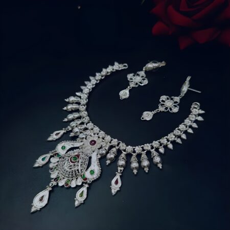 Handcrafted silver-plated necklace set with matching earrings, adorned with red and green enamel teardrop accents, displayed on a black background.
