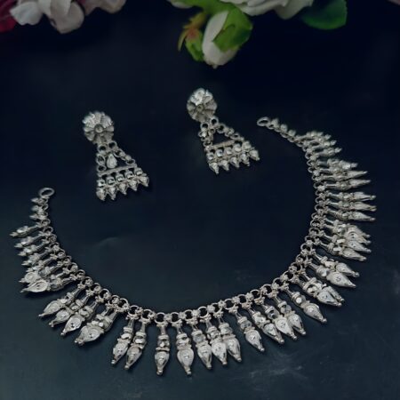 Tribal silver-plated necklace set featuring multiple teardrop and bullet-shaped charms with matching long dangle earrings, displayed on a dark background.