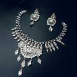 Silver-plated necklace set featuring a crescent moon centerpiece, intricate dome detailing, and matching earrings, displayed on a dark background.