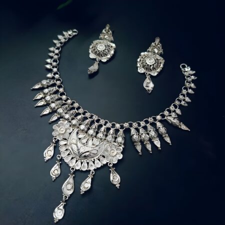 Silver-plated necklace set featuring a crescent moon centerpiece, intricate dome detailing, and matching earrings, displayed on a dark background.