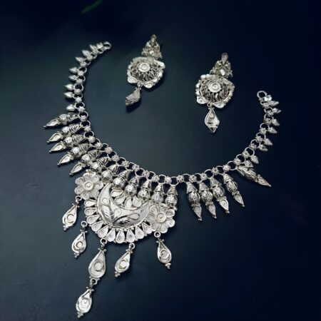 Silver-plated necklace set featuring a crescent moon centerpiece, intricate dome detailing, and matching earrings, displayed on a dark background.