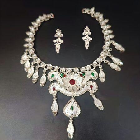 Traditional silver-plated necklace set with a central floral motif, red and green enamel teardrops, and matching drop earrings, displayed on a black background.