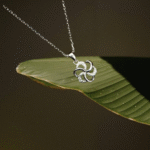 Silver floral swirl pendant locket with a fine chain displayed against a black background.
