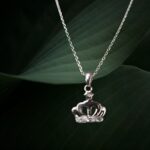 Silver crown-shaped locket necklace with a fine chain on a black background.