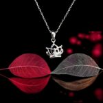 Silver crown-shaped pendant necklace with fine chain on a transparent background.