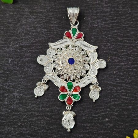 Intricately designed silver locket with floral patterns, red and green enamel detailing, and dangling motifs