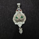 Intricately designed silver locket with floral and leaf patterns, featuring red, blue, and green enamel accents and a detailed hanging motif.