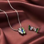 Silver butterfly jewelry set with green and black enamel wings, including a pendant on chain and matching stud earrings with crystal accents.