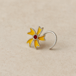 Silver nose pin with a yellow floral design and a red stone at the center, displayed on a neutral background