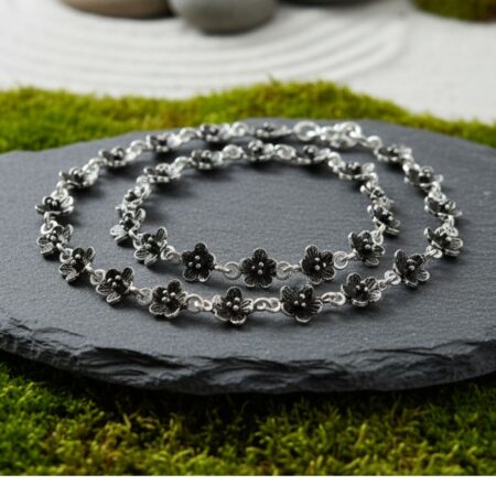 Pair of elegant silver anklets featuring small black floral motifs linked together