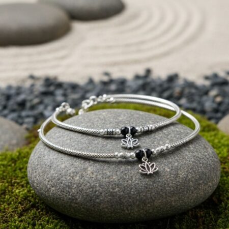 Pair of elegant silver anklets featuring black beads and small lotus-shaped charms