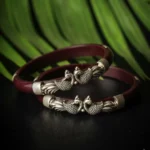 Shop the Maroon Pola Bangle at The VelvetBox. A premium red Beki Pola featuring handcrafted 92.5% silver peacock motifs for a traditional bridal look.